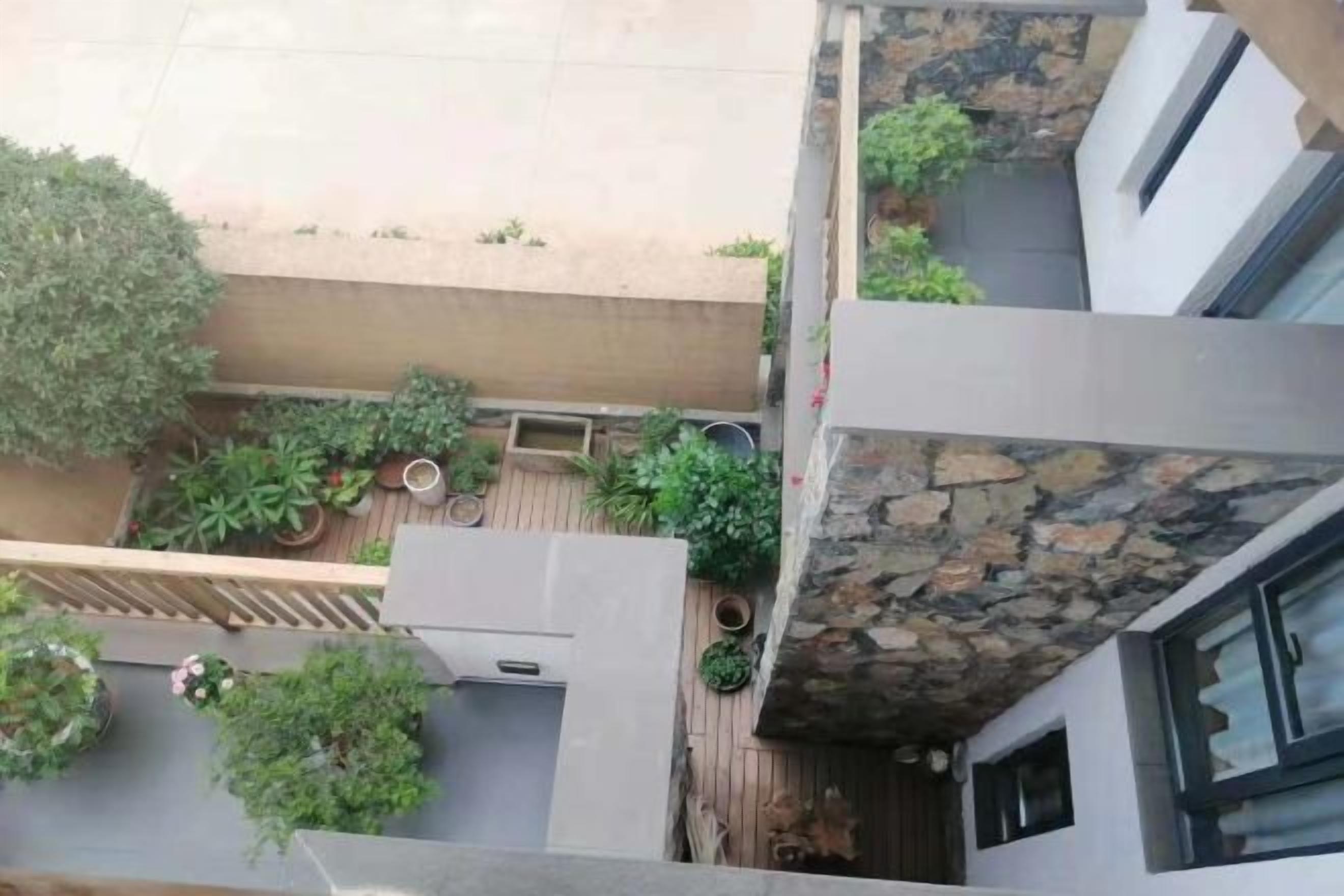 A rooftop terrace with potted plants, a seating area, and a stone wall.