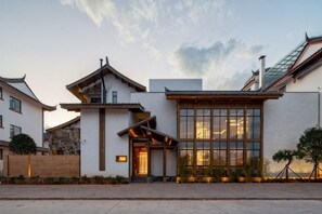 Un edificio de estilo tradicional con un amplio ventanal, entrada de madera y techo inclinado.