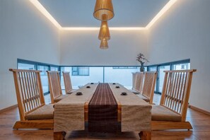 A long dining table with chairs, a hanging light fixture, and large windows. - Mouding Lanyun Homestay (Mouding)