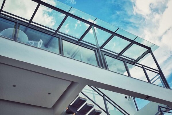 A modern architectural structure with a glass roof and metal framework.
