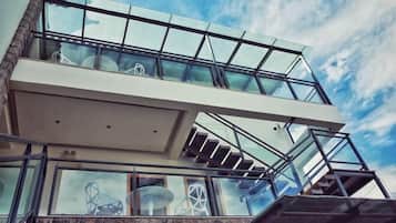 Un edificio moderno con balcón de cristal y escalera que sube a un nivel superior.