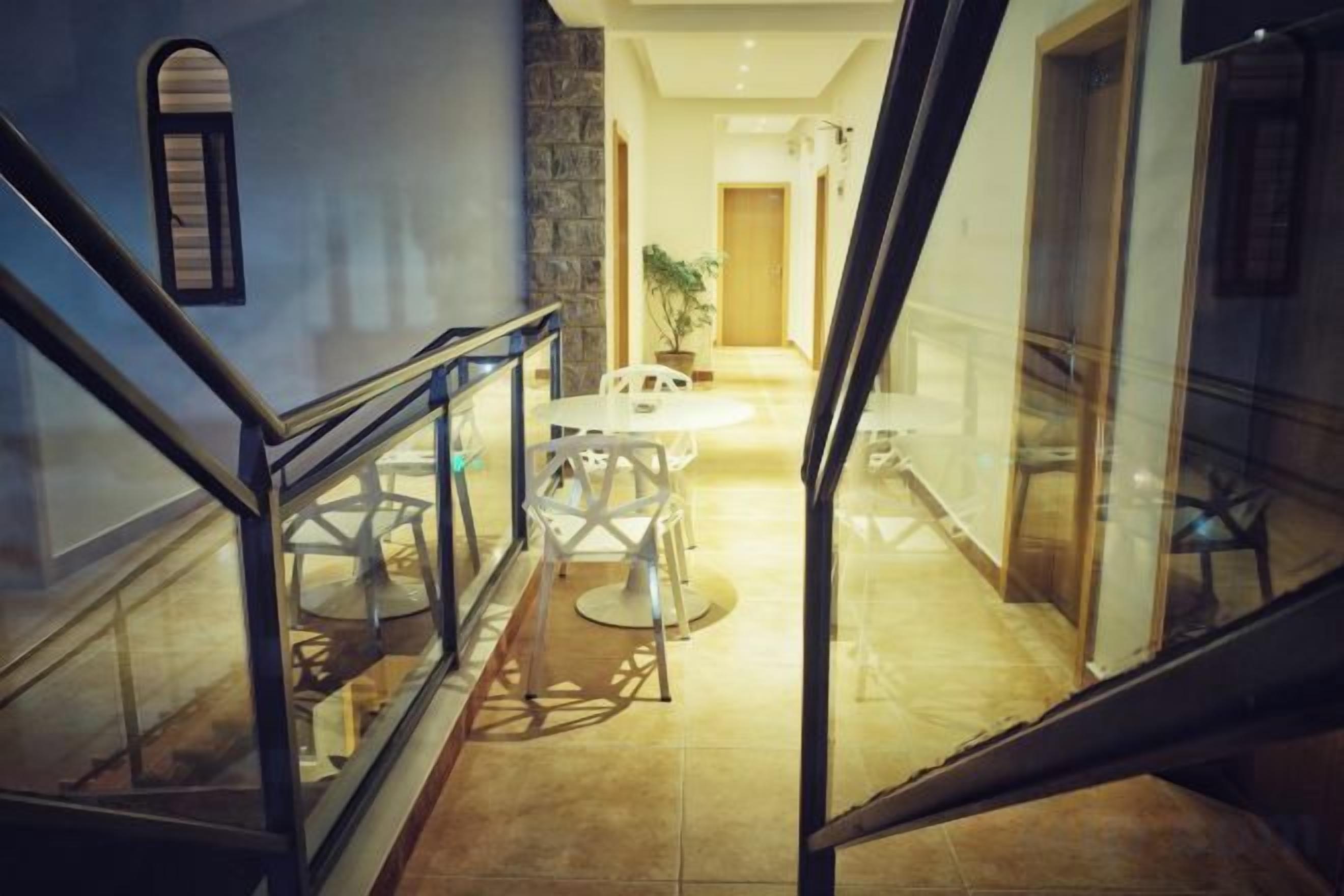 A staircase leading to a dining area with a glass railing, a table, and chairs.