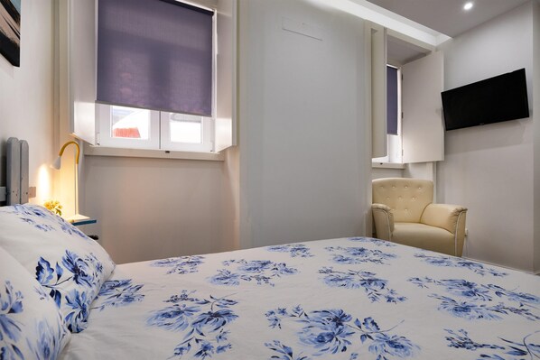 A bedroom with a bed, a chair, a TV, and a window with a blind. - Casa da Ladeira by Trip2Portugal (Figueira da Foz)
