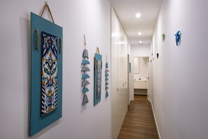 Art-filled hallway with artworks on display, leading to a room with a door and window.