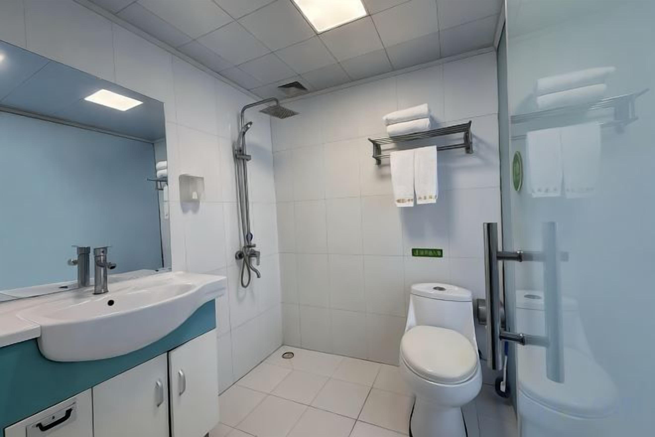 Un baño moderno con lavabo, espejo, ducha, inodoro y cabina de ducha de vidrio.