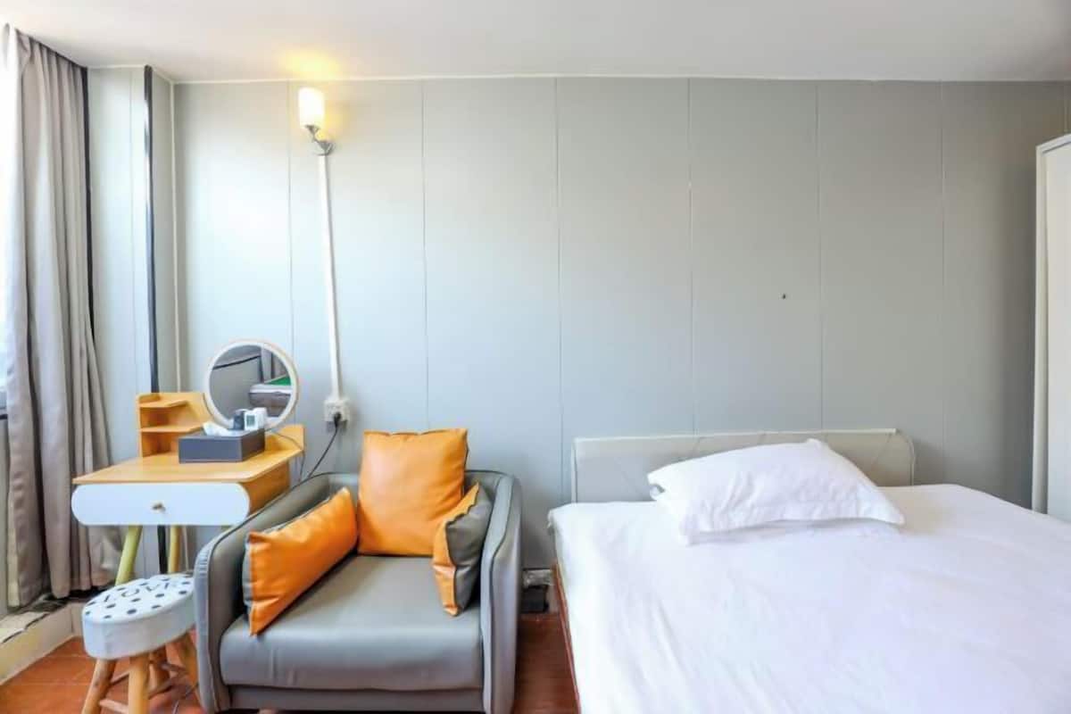 Una habitación de hotel con cama, escritorio con espejo, silla y mesita de noche.