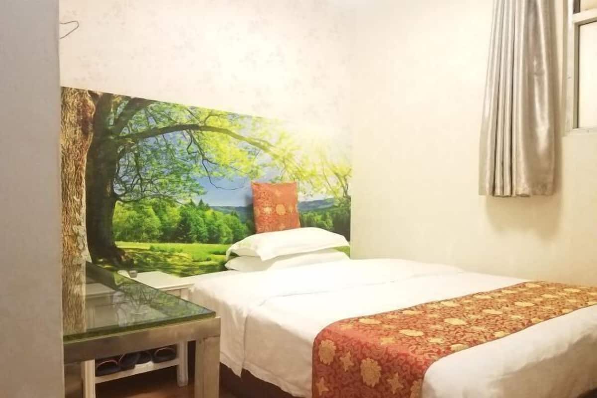 Un dormitorio con una cama, una mesita de noche y un ventanal con cortinas.