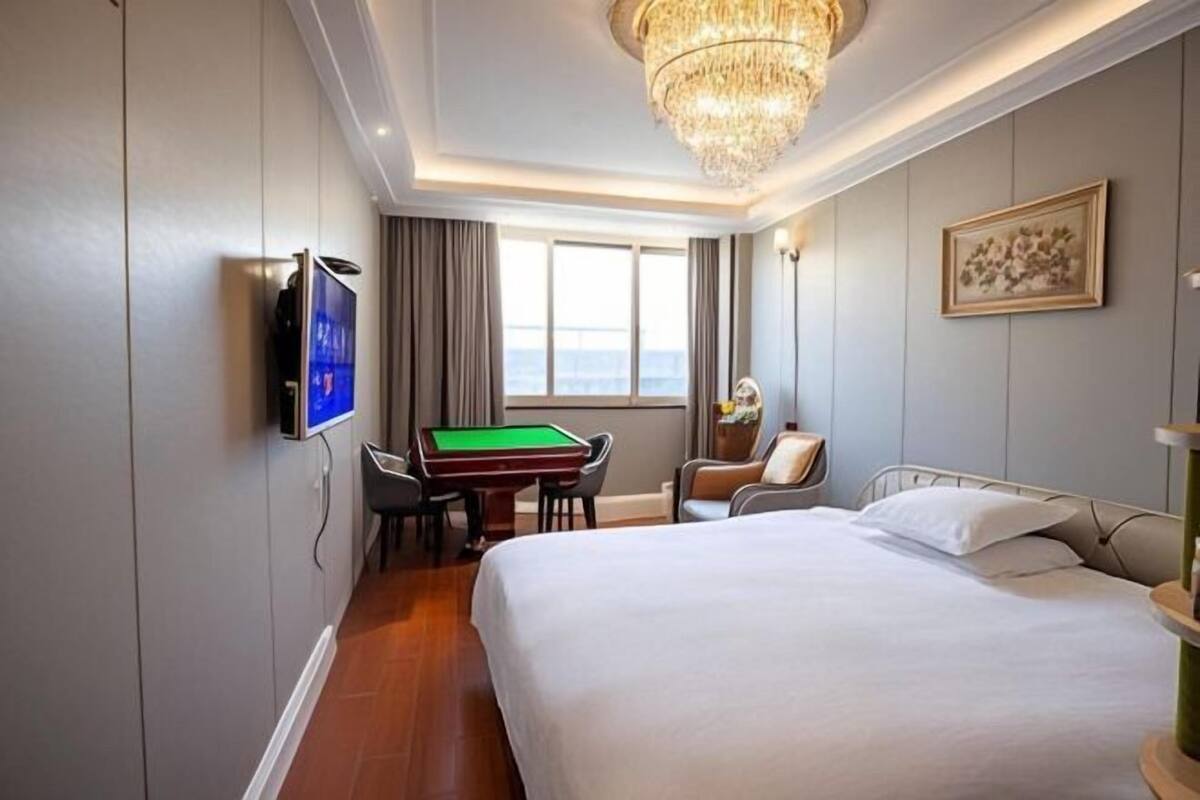 Una habitación de hotel con cama, mesa de billar, televisor y ventana con cortinas.