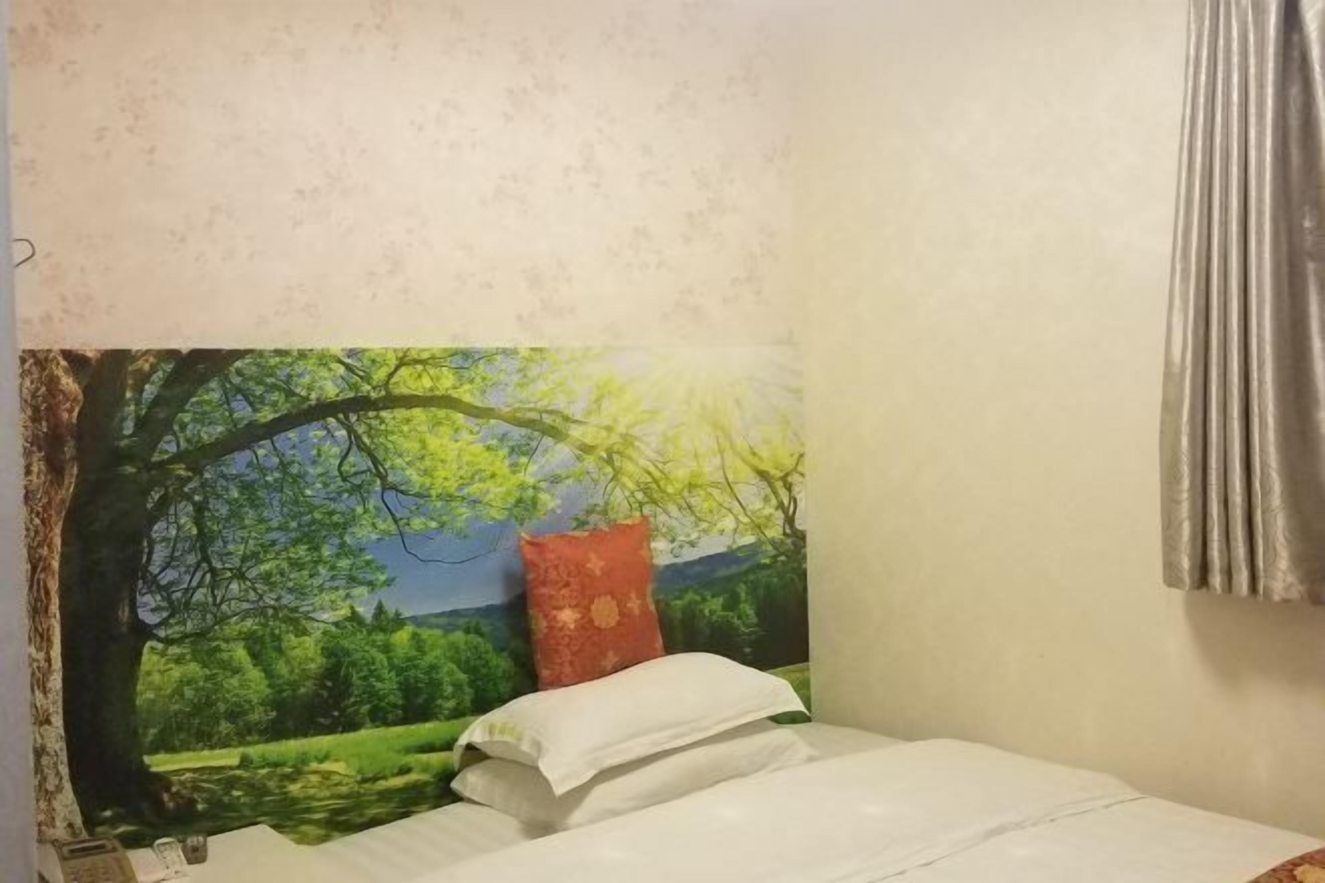 A bedroom with a bed, a window, and a wall mural.