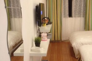A hotel room with two beds, a small desk with a television, a plant, and a window with striped curtains. - Shenzhen Huashang Hotel (Hongling Subway Station KKmall) (Shenzhen)