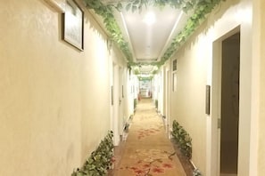 A hallway with a carpet, framed pictures, and a door on the right.