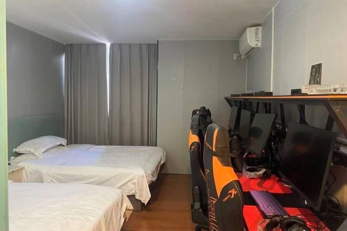 Una habitación con dos camas, un escritorio con computadora y un aire acondicionado.