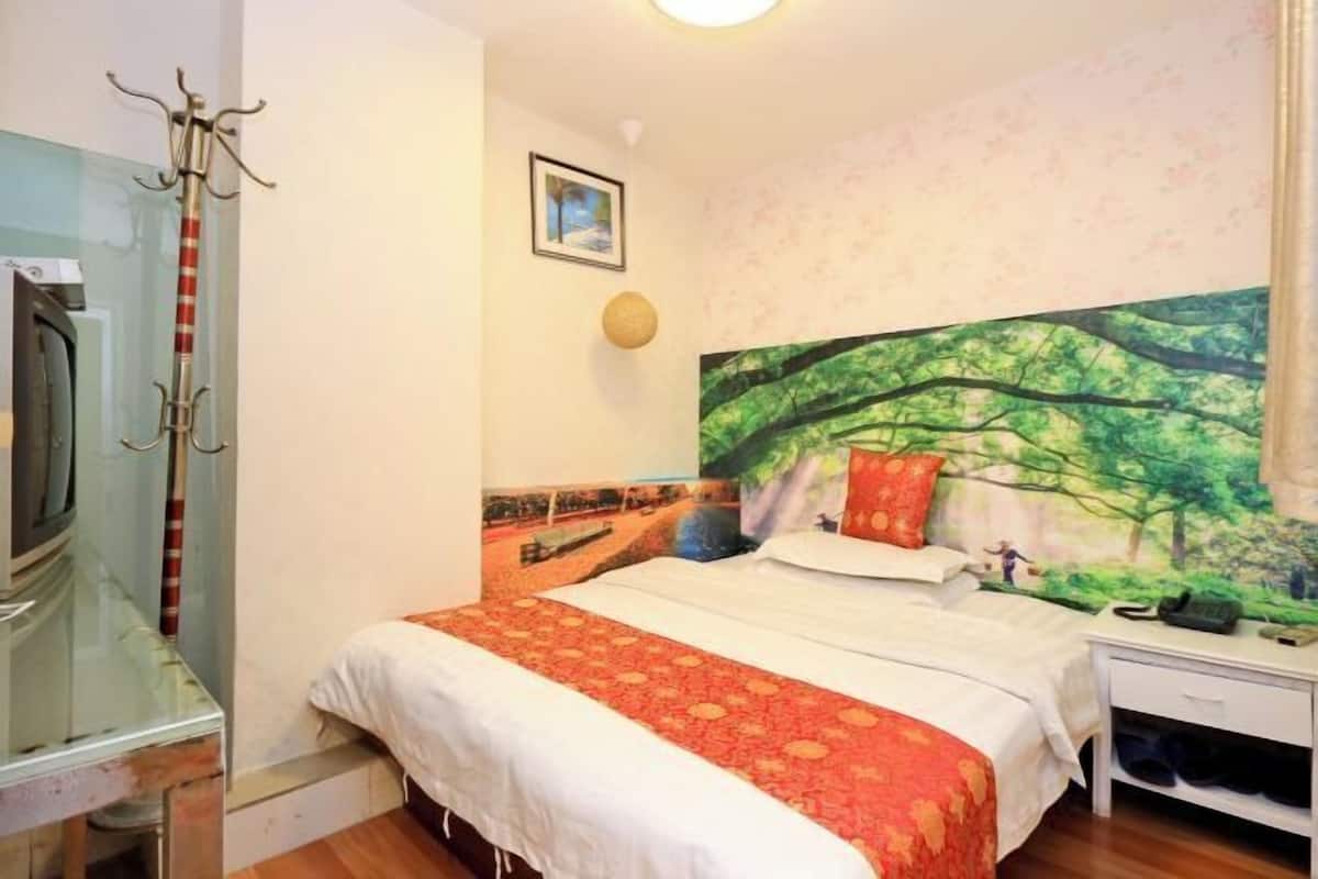 Un dormitorio con una cama, una mesita de noche, un teléfono, un perchero y un cuadro en la pared.