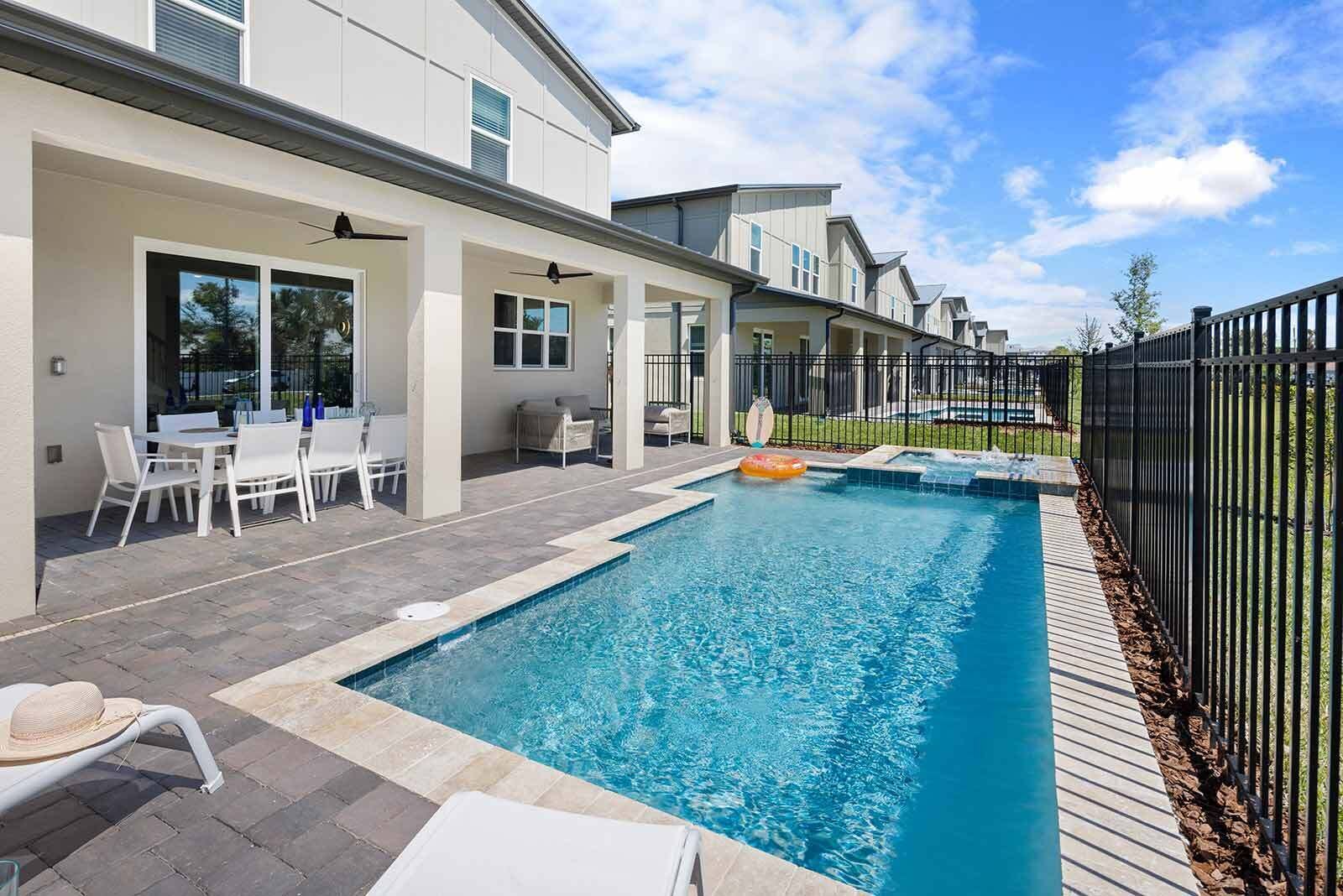 A swimming pool with a lounge area, outdoor seating, and a fenced patio.