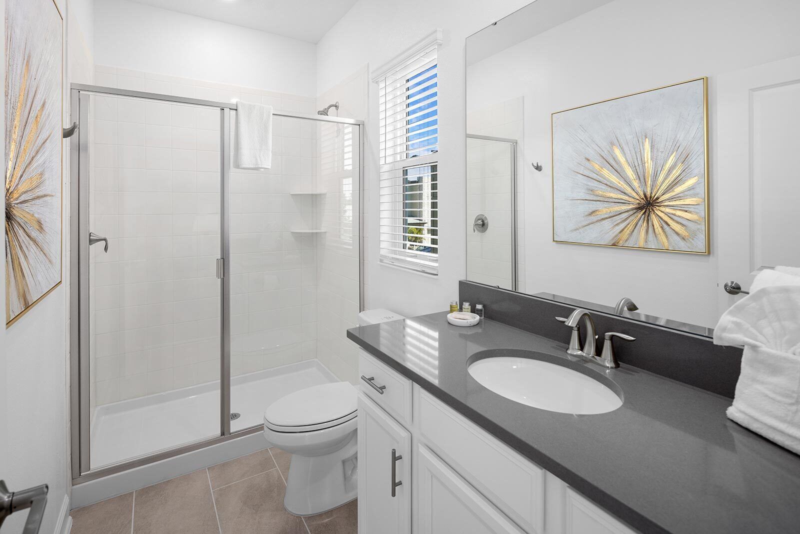 A modern bathroom with a glass-enclosed shower, a white toilet, a vanity with a sink, and a large mirror.