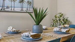 Una mesa de comedor con platos, servilletas y una planta en maceta.
