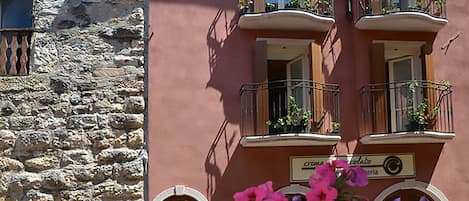 Un edificio con fachada de piedra y una pared rosa con balcones.