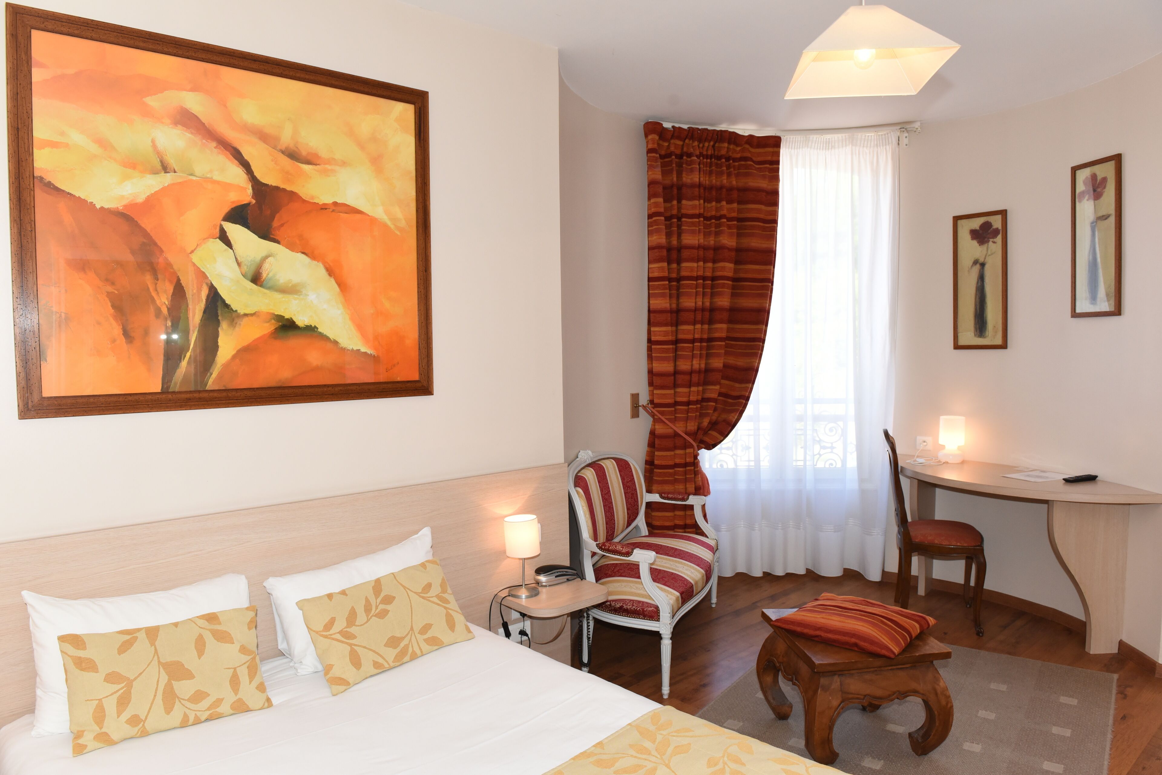 Una habitació d'hotel amb llit, escriptori, cadira, taula petita i un quadre a la paret.