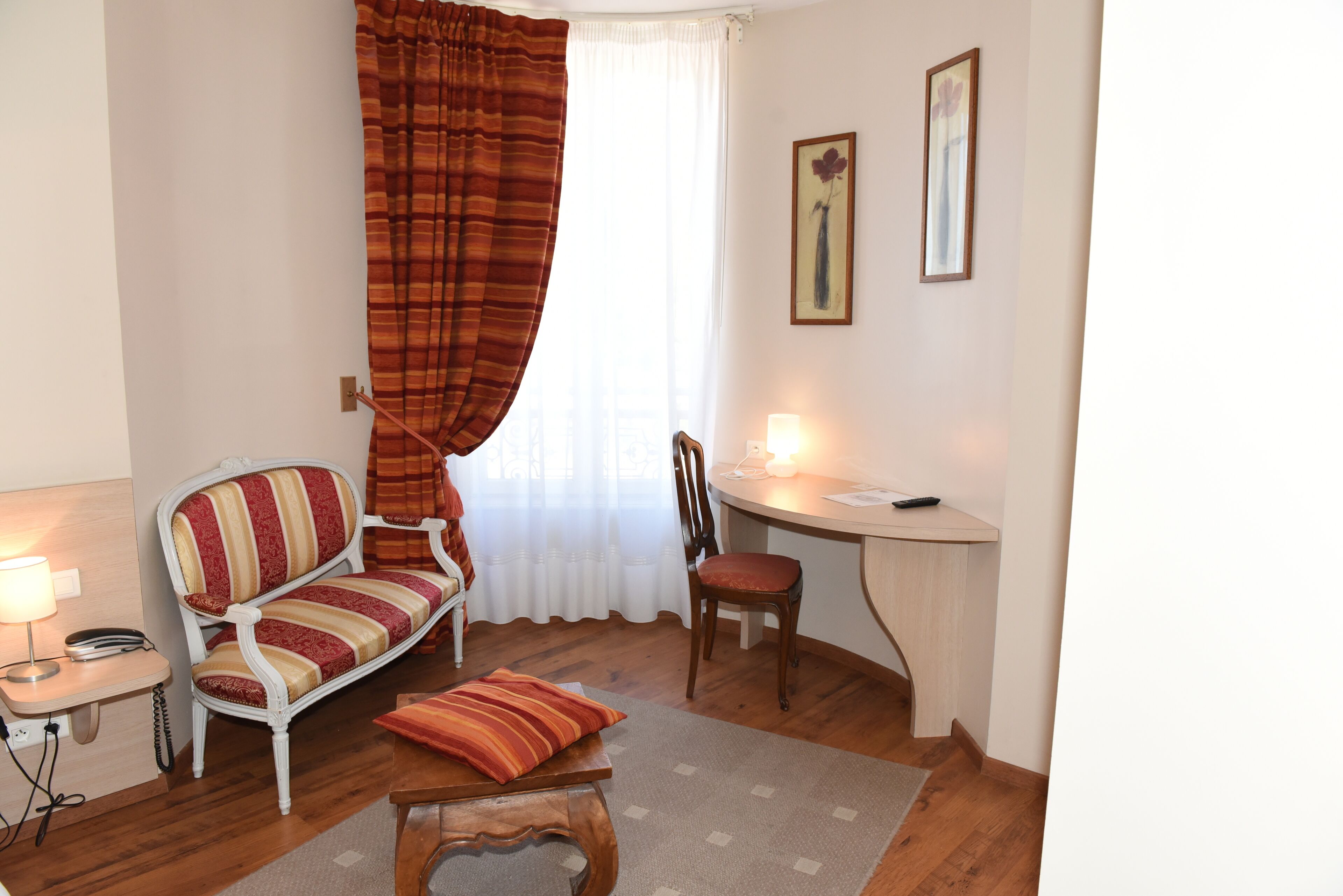 Une pièce avec un canapé à rayures, une chaise en bois, une petite table avec une lampe et un bureau avec une lampe.