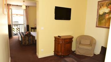 Una habitación con cama, una silla, un televisor y un cuadro.