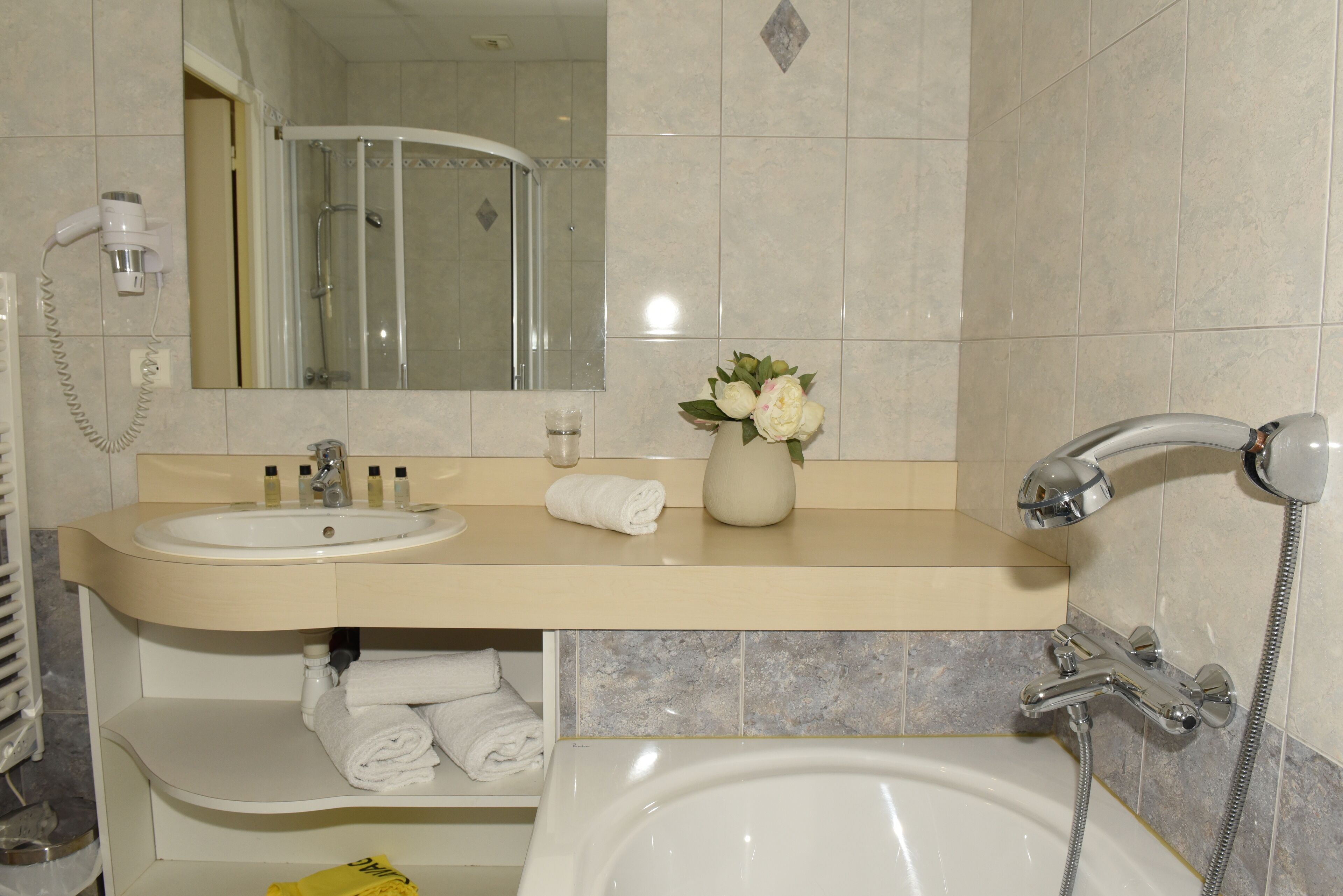 Un baño con lavamanos, espejo, ducha y bañera.