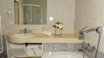Un baño con lavamanos, espejo, ducha y bañera.
