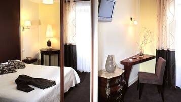 Une chambre d’hôtel comprenant un lit, une table de chevet, une lampe, une télévision, un bureau, une chaise et un vase avec des fleurs.