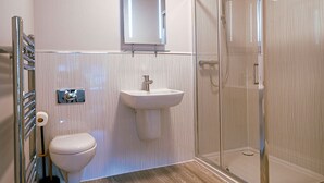A modern bathroom with a toilet, sink, and glass shower enclosure. - Friendship Hotel (Sheffield)