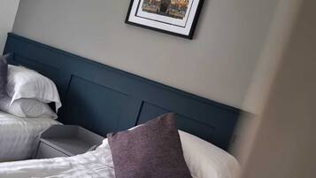 A hotel room with a bed, pillows, a headboard, and a framed picture on the wall.