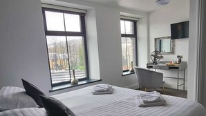 A modern hotel room with a large bed, two windows, a desk, and a television. - Friendship Hotel (Sheffield)