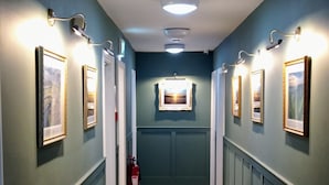 A hallway with wooden flooring, framed pictures on the walls, and recessed lighting. - Friendship Hotel (Sheffield)
