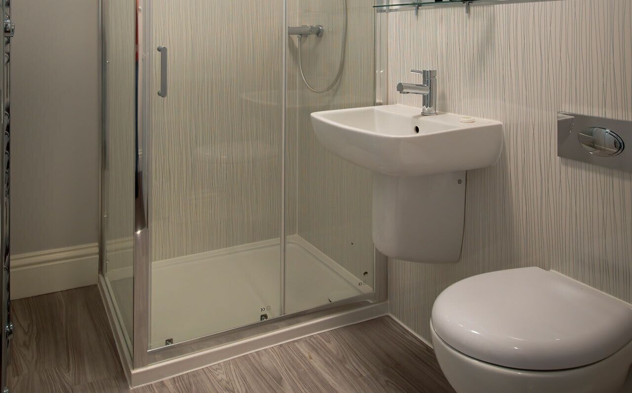 A bathroom with a glass-enclosed shower, a white sink, and a toilet.