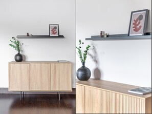 Reception area with a minimalist design, featuring a light wood desk and a vase with green foliage.