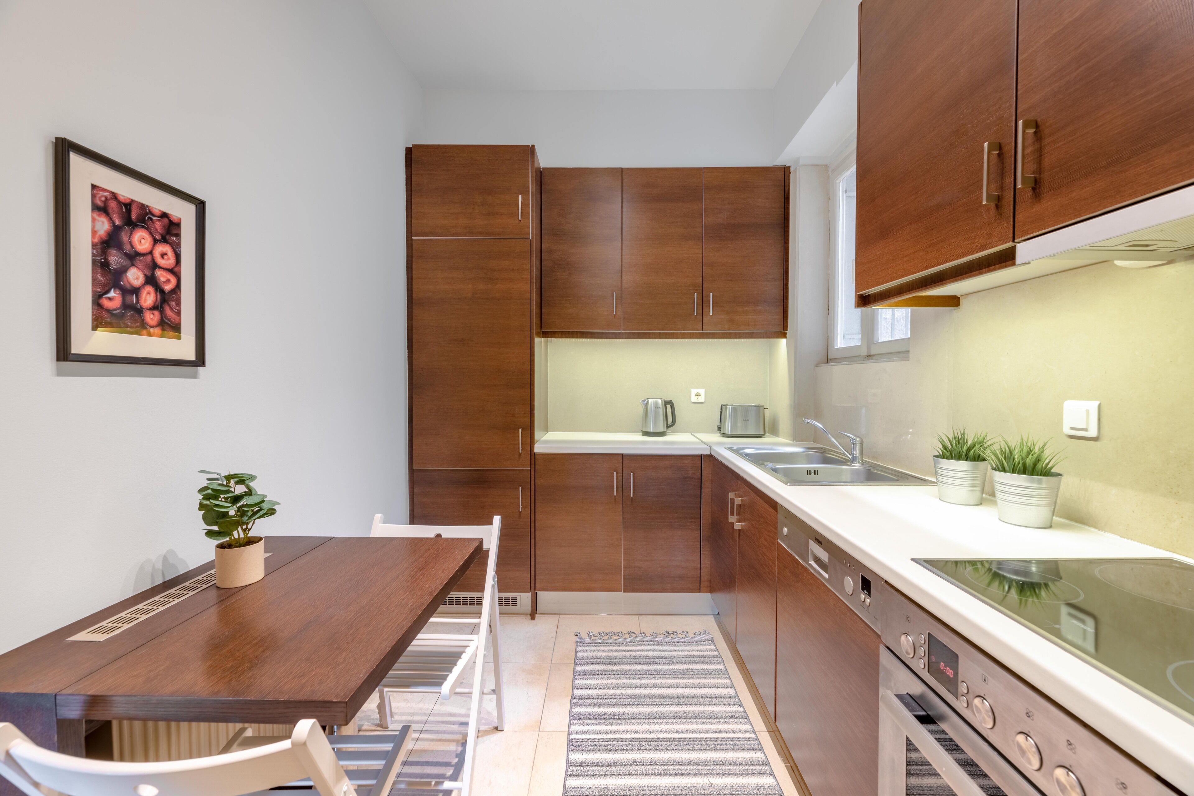 A compact kitchen with wooden cabinets, a white countertop, a stove, and a sink.