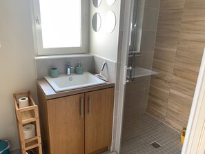 Features a sleek sink, chrome faucet, and glass-enclosed shower.