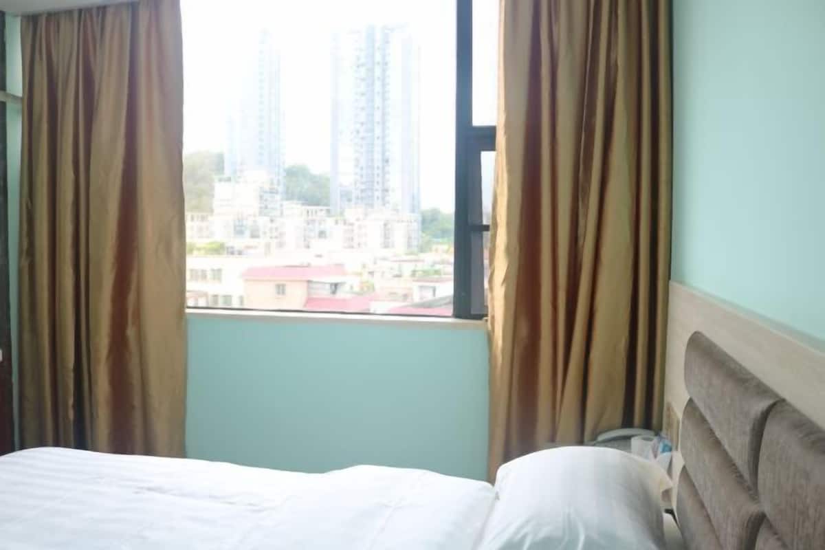 Une chambre d’hôtel avec un lit, des rideaux et une fenêtre donnant sur des immeubles.