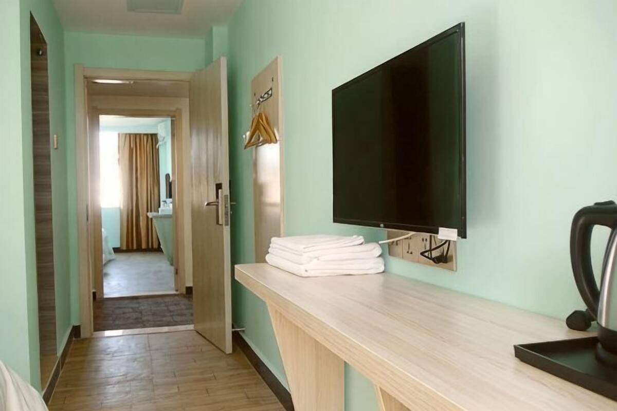 Une chambre d’hôtel équipée d’un bureau en bois, d’un téléviseur à écran plat et d’un porte-serviettes.