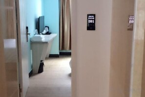 A hotel hallway with a sink and mirror, a sign indicating room number 201, and a door to the right.