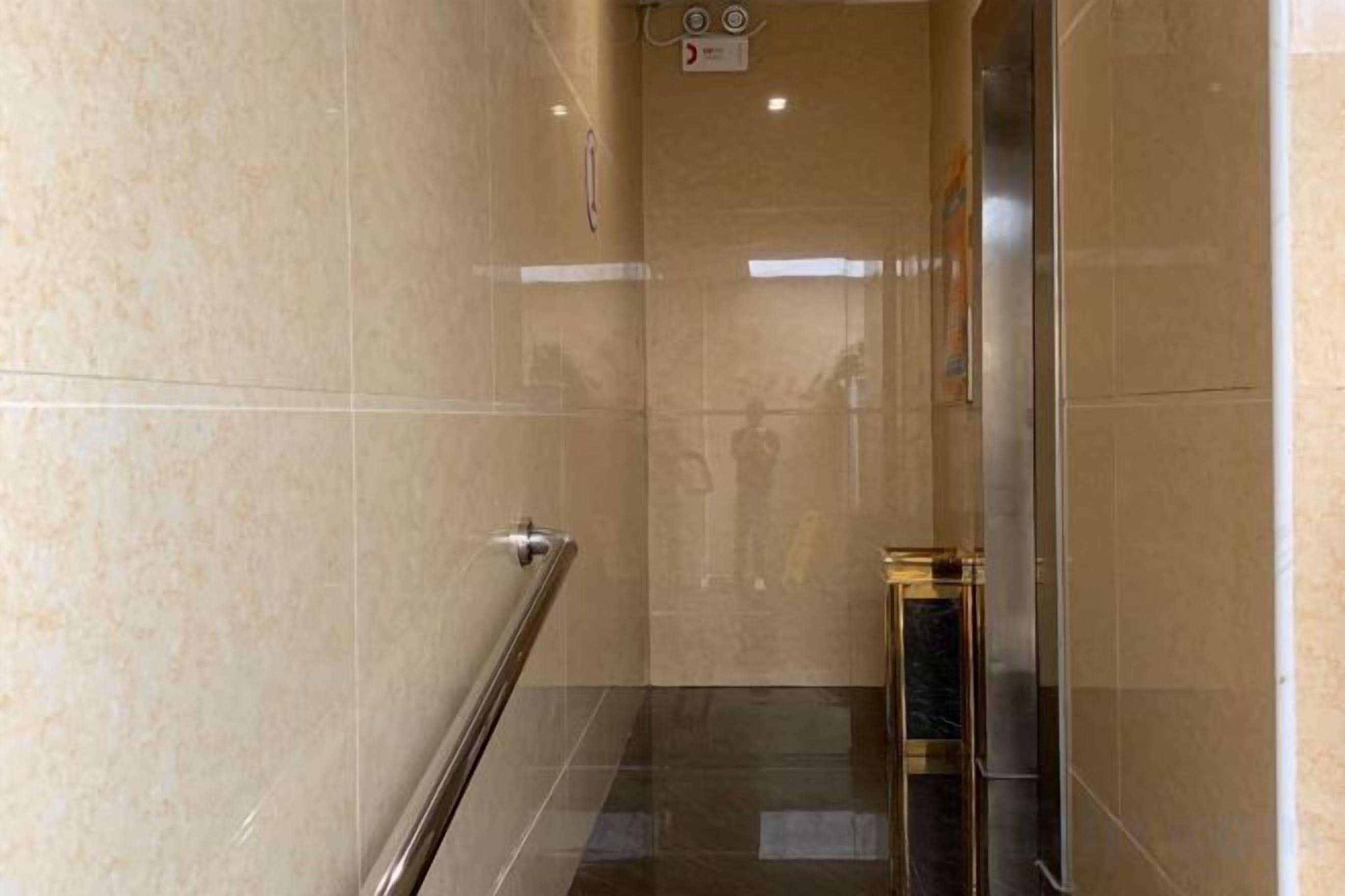 A corridor with a handrail and a door at the end.
