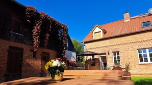 Eine hölzerne Bank mit einem Blumentopf, ein Backsteinhaus und ein weißes Haus mit rotem Dach.