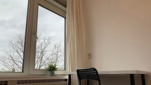 A room with a window, a radiator, a chair, and a potted plant. - TU Delft Daisy room 4 (Delft)