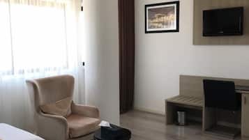 Habitación de hotel con dos camas, un escritorio, una silla, un televisor y una ventana con cortinas.