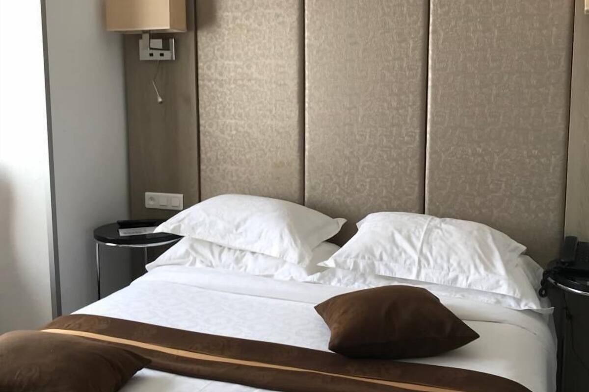 A hotel room with a large bed, a bedside table, a lamp, and a telephone.