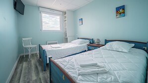 A bedroom with two beds, a window, a TV, and a small table.