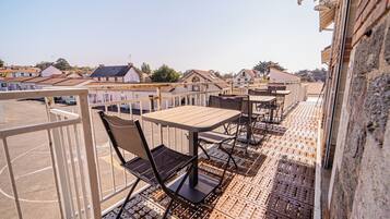 Une terrasse sur le toit, avec des tables et des chaises, offrant une vue sur les bâtiments environnants, et un mur en briques.