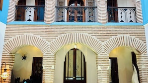 A multi-level building with a central courtyard, featuring brick arches and a balcony with decorative railings. - Riad Zarka (Marrakech)