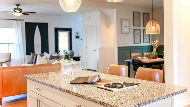 Una cucina con piani di lavoro in granito, un'area pranzo con tavolo e sedie, e illuminazione a sospensione.