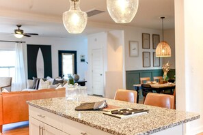 Una cocina con encimeras de granito, un comedor con mesa y sillas, e iluminación colgante.