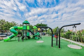 Uma área de recreação com escorregador, estruturas para escalar e balanços.