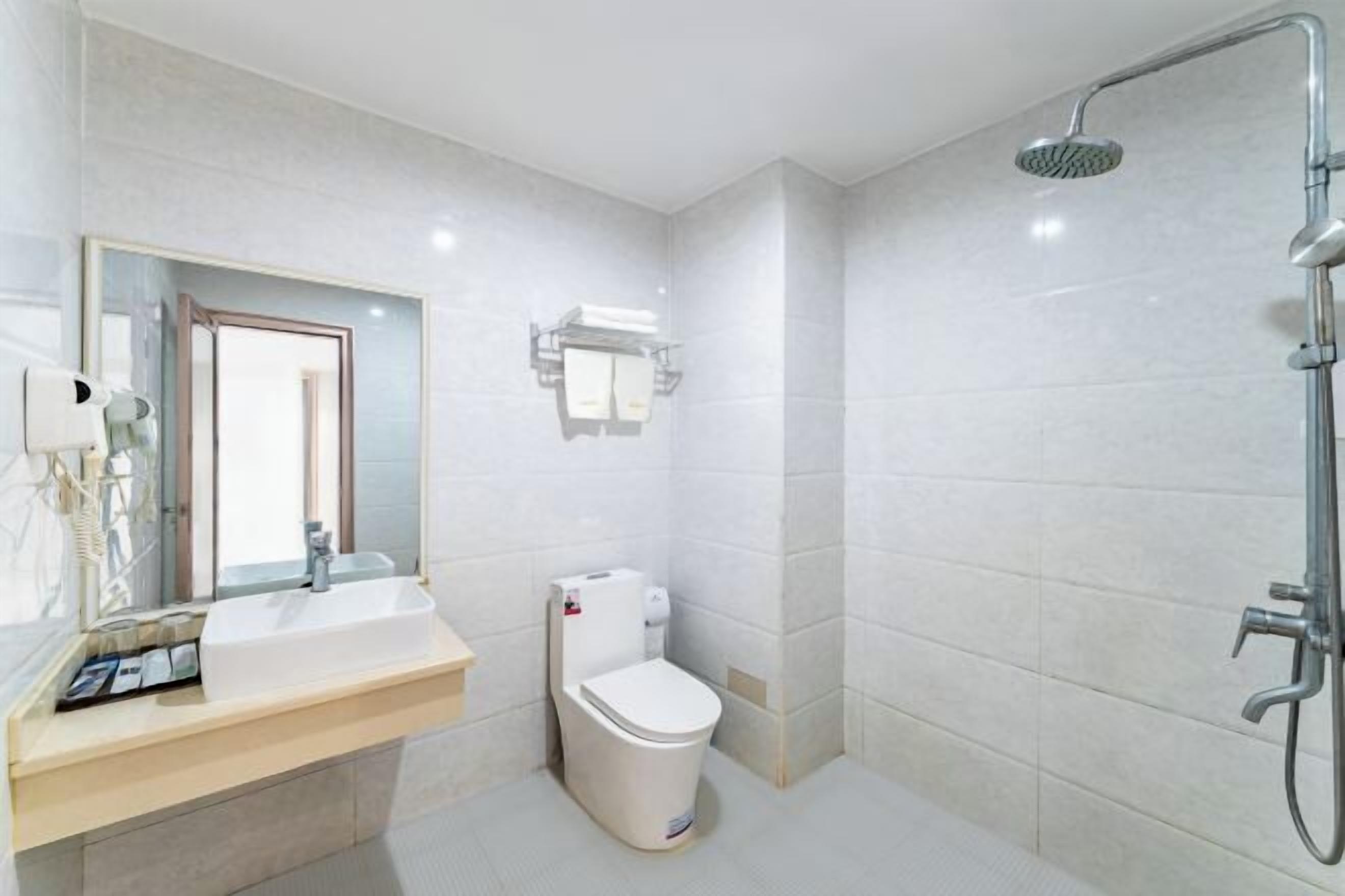 Un baño moderno con un lavamanos, espejo y retrete blancos.